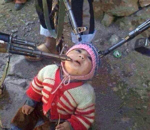 A child is photographed, waiting to be killed by militants. ISIS uses these images to terrorize others and to glorify their spree of terror.