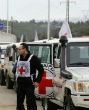 Image of Rebel fighters inspected the aid vehicles in the freezing rain before they were allowed to enter.