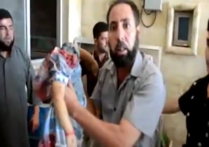 A distraught father in Syria holds the lifeless body of his decapitated daughter, executed by milita