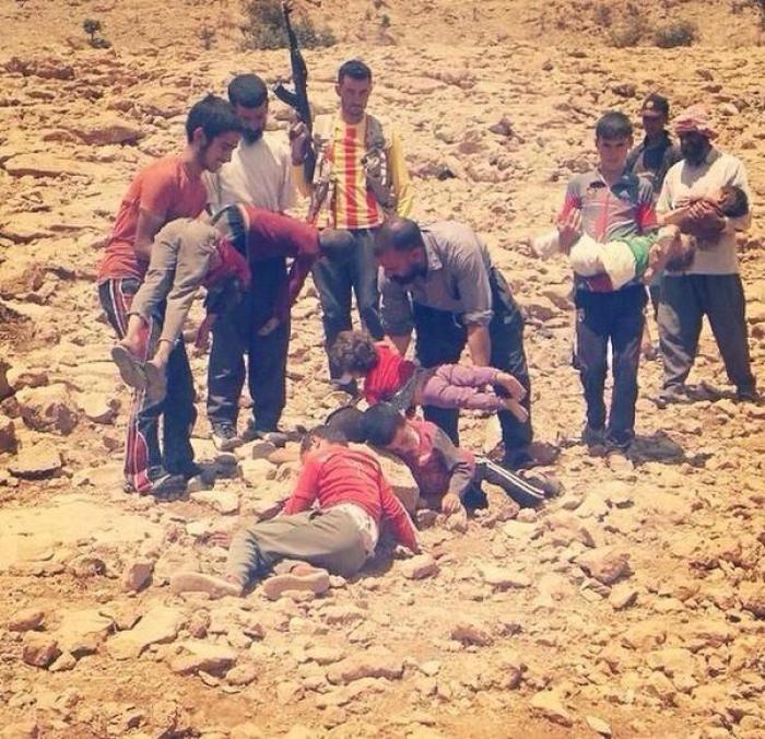 Kurdish men carry the bodies of children who died after being driven from their homes with nothing t