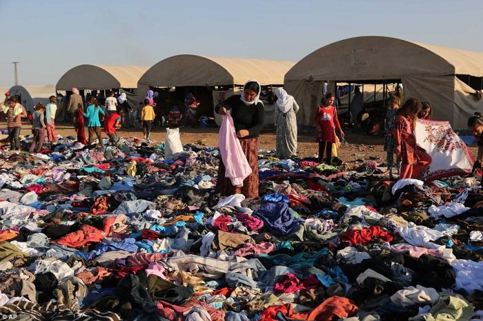 Displaced Iraqis from the Yazidi community look for clothes to wear among items provided by a charit Displaced Iraqis from the Yazidi community look for clothes to wear among items provided by a charit