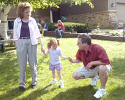 Jeanne and Neal Binsfeld guide their daughter, Hannah, 5, as she walks in the family's front yard July 12. Hannah, adopted at 9 months, is blind and has epilepsy. (The Catholic Spirit Photo/Dianne Towalski) Image of Jeanne and Neal Binsfeld guide their daughter, Hannah, 5, as she walks in the family's front yard July 12. Hannah, adopted at 9 months, is blind and has epilepsy. (The Catholic Spirit Photo/Dianne Towalski)