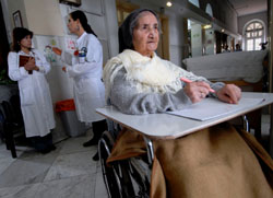 PATIENT WRITES OUT PRAYERS AT JERUSALEM HOSPICE FACILITY – Sister Constancia Francis, 82, writes out prayers as therapist Tammy Einstein, center, consults with another staff member at Saint-Louis Hospital in Jerusalem March 22. The facility, run by the Sisters of St. Joseph of the Apparition, provides hospice and geriatric care to Jerusalem residents of any race, religion or nationality. (CNS photo/Debbie Hill) PATIENT WRITES OUT PRAYERS AT JERUSALEM HOSPICE FACILITY – Sister Constancia Francis, 82, writes out prayers as therapist Tammy Einstein, center, consults with another staff member at Saint-Louis Hospital in Jerusalem March 22. The facility, run by the Sisters of St. Joseph of the Apparition, provides hospice and geriatric care to Jerusalem residents of any race, religion or nationality. (CNS photo/Debbie Hill)