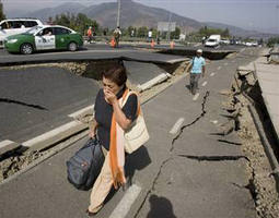 A woman walks by a destroyed road in Santiago, Chile, after a magnitude 8.8 earthquake hit the country early Saturday. Image of A woman walks by a destroyed road in Santiago, Chile, after a magnitude 8.8 earthquake hit the country early Saturday.