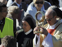 Local priest carries the consecrated host in a procession before about 1000 of the Catholic faithful in Poland Local priest carries the consecrated host in a procession before about 1000 of the Catholic faithful in Poland