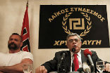 Nikolaos Michaloliakos speaking at a conference for Golden Dawn. Image of Nikolaos Michaloliakos speaking at a conference for Golden Dawn.