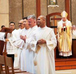 Fathers Manuel Bravo, Chan Woo Lee, Eben MacDonald and Nabor Rios turn to the assembly gathered for their ordination to the priesthood June 2. VICTOR ALEMAN Fathers Manuel Bravo, Chan Woo Lee, Eben MacDonald and Nabor Rios turn to the assembly gathered for their ordination to the priesthood June 2. VICTOR ALEMAN