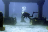 Divers swim through an artificial version of Atlantis in the Caribbean. Image of Divers swim through an artificial version of Atlantis in the Caribbean.