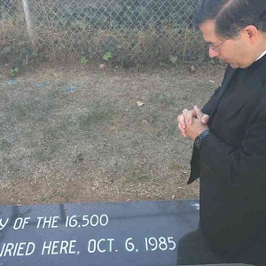 Fr. Pavone prays at the graveside of the children Fr. Pavone prays at the graveside of the children