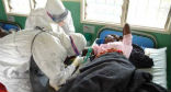 Aid workers in protective clothing treat a woman infected with the Ebola virus. Image of Aid workers in protective clothing treat a woman infected with the Ebola virus.