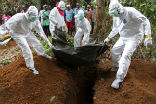 Aid workers in Liberia bury the body of an Ebola victim. Image of Aid workers in Liberia bury the body of an Ebola victim.