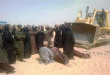 Coptic monks lie before bulldozers as workers chant Image of Coptic monks lie before bulldozers as workers chant