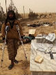 ISIS militant stands with the help of crutches beside destroyed Christian headstone. Image of ISIS militant stands with the help of crutches beside destroyed Christian headstone.