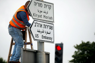 A worker posts signs to direct people to the new U.S. embassy in Jerusalem. A worker posts signs to direct people to the new U.S. embassy in Jerusalem.