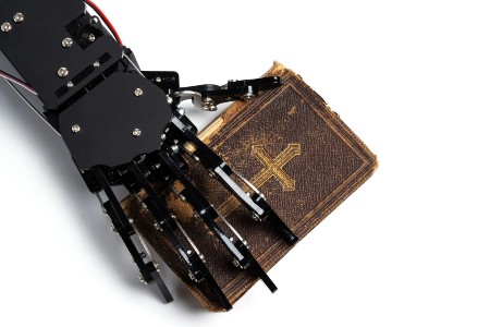 Real AI robot's hand with the ancient Bible. Image of Real AI robot's hand with the ancient Bible.