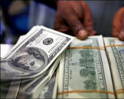 A money changer displays stacks of 100 US dollar bills at a foreign exchange counter. Image of A money changer displays stacks of 100 US dollar bills at a foreign exchange counter.