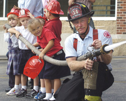 KINDERGARTENERS GET HANDS-ON DEMONSTRATION – Four-year-old kindergarten students from Blessed Sacrament School get a hands-on demonstration of a water hose from firefighter Richard Vanwieringen, right, and Lt. Thomas Kizewski of the Milwaukee Fire Department Sept. 15. Fire department representatives visited the school after kindergarten students reported a house fire across the street from the school's playground during recess Sept. 13. (Catholic Herald) Image of KINDERGARTENERS GET HANDS-ON DEMONSTRATION – Four-year-old kindergarten students from Blessed Sacrament School get a hands-on demonstration of a water hose from firefighter Richard Vanwieringen, right, and Lt. Thomas Kizewski of the Milwaukee Fire Department Sept. 15. Fire department representatives visited the school after kindergarten students reported a house fire across the street from the school's playground during recess Sept. 13. (Catholic Herald)