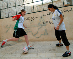 WOMEN PLAY SOCCER ON STREET IN BETHLEHEM - Marian Al Bandak, 17, and her neighbor, Honey Thaljieh, 22, play soccer on the street between their houses in Bethlehem in the West Bank Dec. 6. Both are members of the Palestinian Women's National Soccer League. Although Palestinians have traditionally regarded soccer as a man's sport, younger generations of women have defied tradition and often the will of their families by playing the sport. (CNS photo/Debbie Hill) Image of WOMEN PLAY SOCCER ON STREET IN BETHLEHEM - Marian Al Bandak, 17, and her neighbor, Honey Thaljieh, 22, play soccer on the street between their houses in Bethlehem in the West Bank Dec. 6. Both are members of the Palestinian Women's National Soccer League. Although Palestinians have traditionally regarded soccer as a man's sport, younger generations of women have defied tradition and often the will of their families by playing the sport. (CNS photo/Debbie Hill)