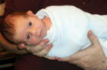 A baby swaddled and held for vaccinations. Image of A baby swaddled and held for vaccinations.