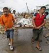 Workers carry the body of a victim to a collection area. Image of Workers carry the body of a victim to a collection area.