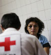 A woman waits for a Red Cross worker to provide treatment following a brutal rape and beating. Image of A woman waits for a Red Cross worker to provide treatment following a brutal rape and beating.