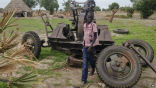 A child plays around an abandoned anti-aircraft gun parked in a fallow field. Image of A child plays around an abandoned anti-aircraft gun parked in a fallow field.