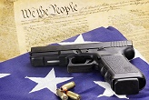 Gun on an American flag with the U.S. Constitution in the background Image of Gun on an American flag with the U.S. Constitution in the background