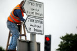 A worker posts signs to direct people to the new U.S. embassy in Jerusalem. Image of A worker posts signs to direct people to the new U.S. embassy in Jerusalem.