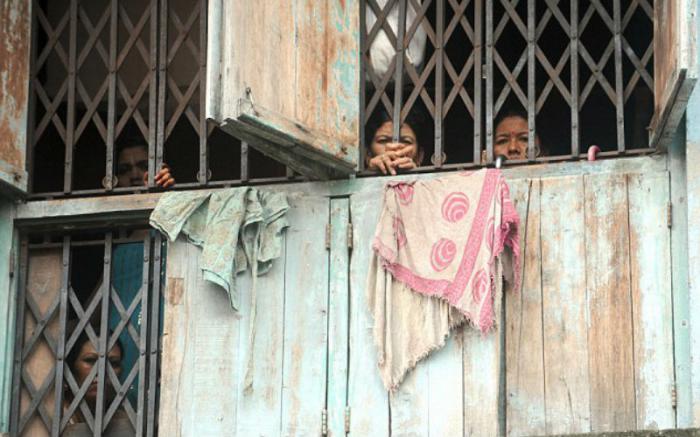 Indian sex workers peer out from a brothel in Mumbai. Indian sex workers peer out from a brothel in Mumbai.