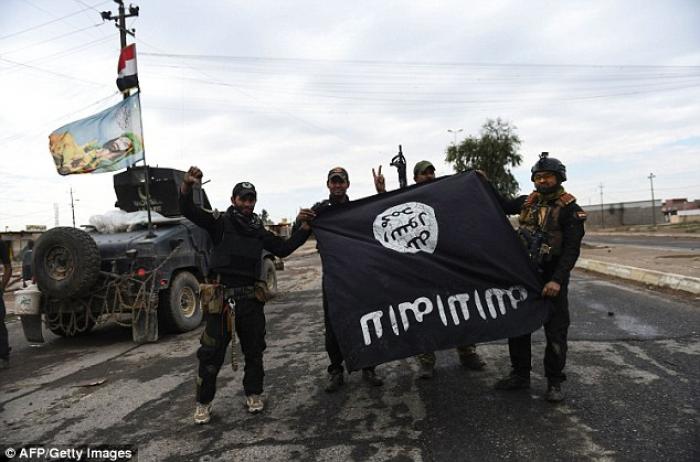 Iraqi soldiers display a captured ISIS standard. Iraqi soldiers display a captured ISIS standard.