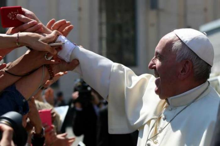 Pope Francis hands rosaries to pilgrims in St. Peter's Square.