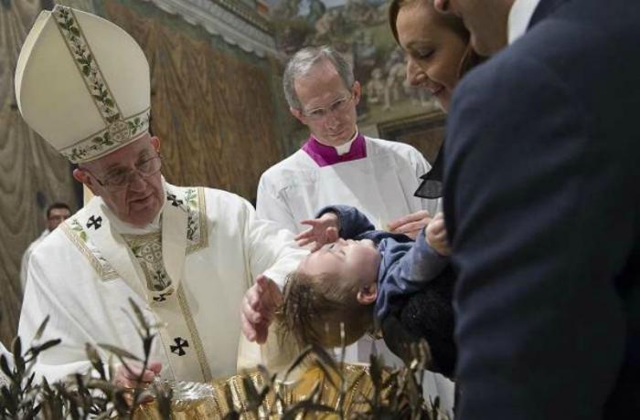 Pope Francis baptizes a baby in the Sistine Chapel.