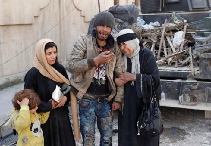 A family trying to escape fighting between Iraqi forces and ISIS fighters cry on a street in Mosul, Iraq.