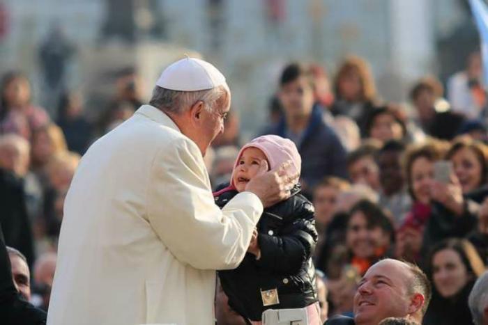 Pope Francis kisses a child in St. Peter's Square for the general audience.