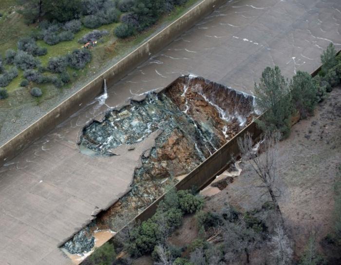 Fig 9. Original 'Blow-out' failure of Main Spillway. No 'Large Blocks' present. The upper failure seam in the spillway is where seepage has been observed originating in the spillway during non-operating conditions (dry - See Fig 14). This seam is also where multiple repairs have been performed over the years as evidenced in images of 'cuts' in the slab concrete for nearly the full length of this seam. After additional flows of 30,000 cfs to 33,000 cfs on Feb 8, 2017, and then 45,000 cfs on Feb 9, 2017, is when rapid upslope spillway backcutting collapsing failure progressed. This 'rapid upslope' spillway collapse was most likely accelerated by the unstable large 'void fill' blocks that had little to no anchor bar integrity remaining. The spillway flow was stopped on Feb 10, 2017 for an inspection (See Fig 8.). That is when the stack of 'large slab blocks' were observed washed to the far side of the erosion channel, abutting the still intact broken upper part of the lower spillway. This is the critical evidence that the 'large slab blocks' originated just above this 'original blow-out failure' location & in the same large highly erodible weathered rock seam (Fig 8.).