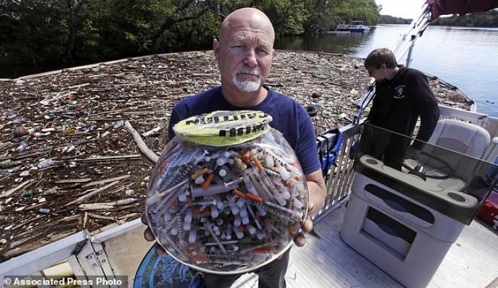 Rocky Morrison, from the Clean River Project in Methuen, Massachusetts holds up a bowl of syringes he has found. The bowl provides a shocking example of how plentiful discarded needles are. 