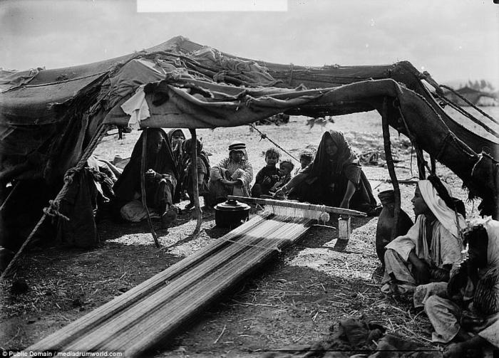 A Bedouin woman weaves under a tent. 