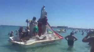 Fr. Don Mario Calogiuri blesses swimmers from his paddle boat.