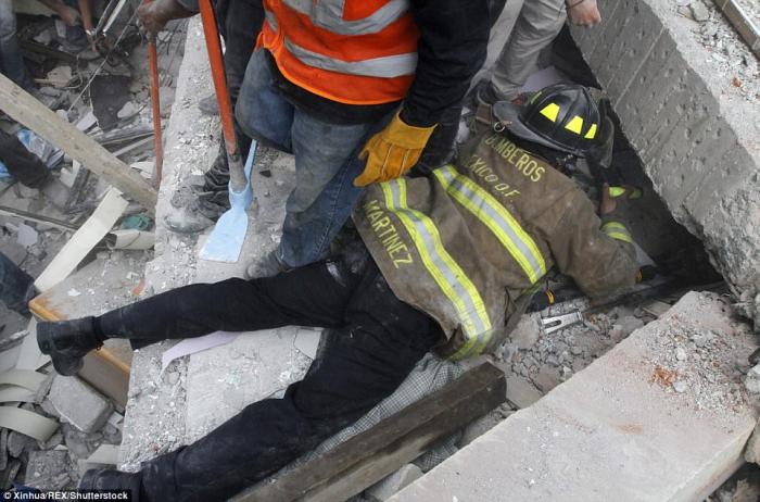 A firefighter works to rescue a person trapped under the debris of a collapsed building. 