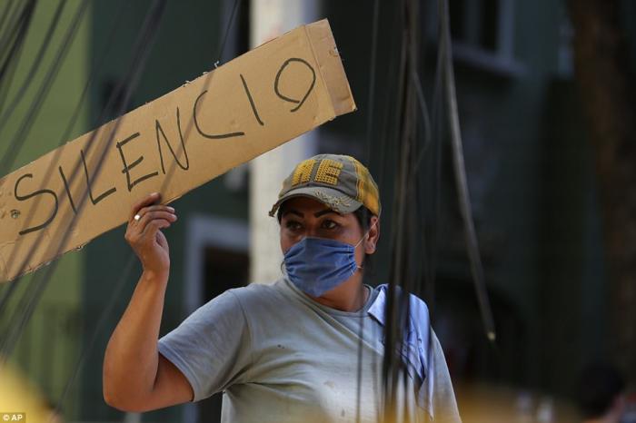 A worker holds up a sign calling for silence. Workers periodically asked the crowds to be silent so they could listen for the cries of people trapped in the rubble. 