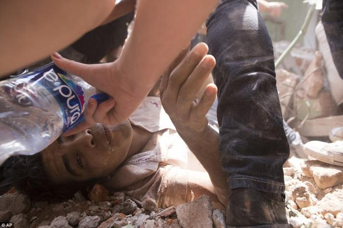 A trapped man is given water before he is removed from the rubble and taken to the hospital. A trapped man is given water before he is removed from the rubble and taken to the hospital.