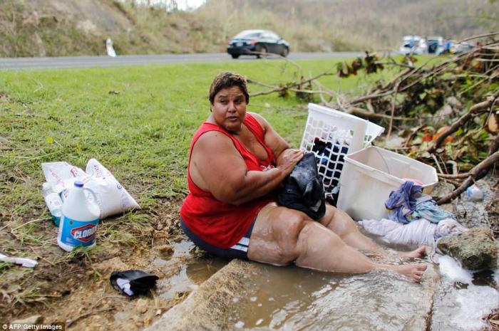 A woman does laundry in a flooded gutter. The island remains without water. A woman does laundry in a flooded gutter. The island remains without water.