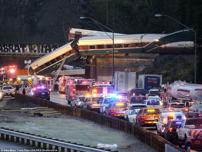 Thirteen of the train's fourteen cars derailed, with one tumbling onto the tracks below, and another dangling off the overpass. 
