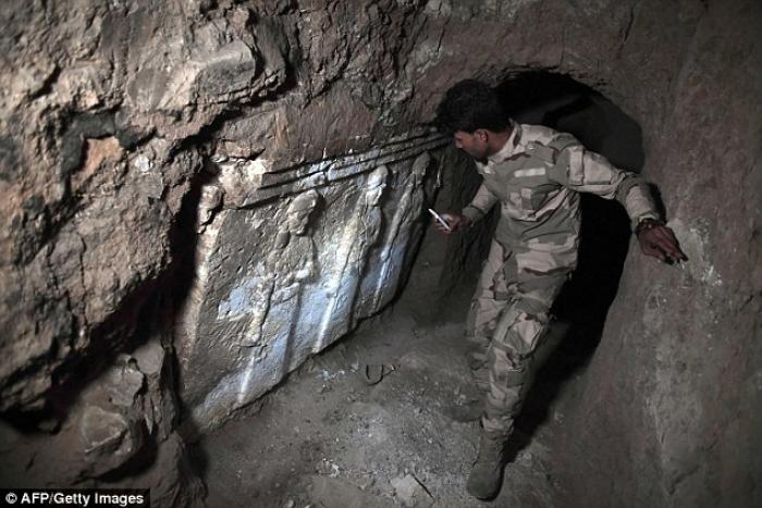 An Iraqi soldier stands next to a sculpture depicting Assyrian goddesses in King Esarhaddon's palace. 