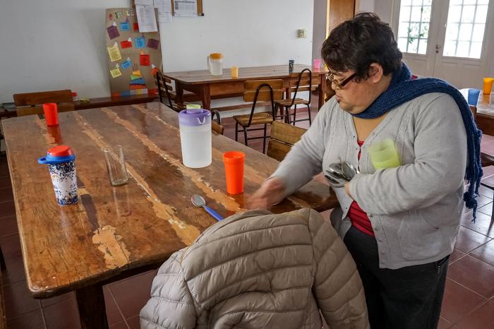 Sandra Cardozo, una usuaria regular del Centro de Dia de la Fundacion IPNA, pone la mesa antes de una comida en el comedor del centro.