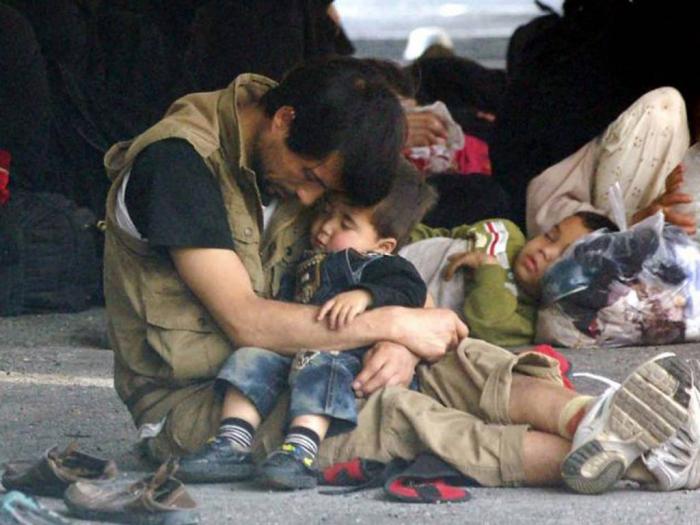 A Muslim migrant holds his son as they are detained at the Immigration Police Office on the Thai-Mal A Muslim migrant holds his son as they are detained at the Immigration Police Office on the Thai-Mal