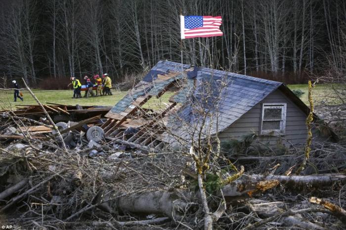 Here rescue workers are seen removing a body from the wreckage of homes destroyed by a mudslide near Here rescue workers are seen removing a body from the wreckage of homes destroyed by a mudslide near