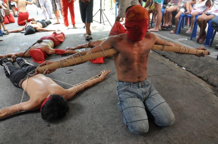 Devotees with wooden stakes tied to their arms pray during a painful ritual as part of the observanc Devotees with wooden stakes tied to their arms pray during a painful ritual as part of the observanc
